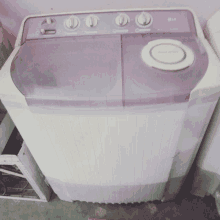 a purple and white lg washing machine sits on a concrete floor