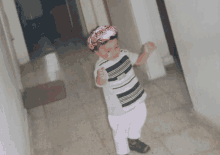 a young boy wearing a pink headband stands in a hallway with his fist in the air