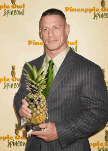 a man in a suit and tie is holding a pineapple with an owl on it