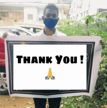 a man wearing a blue mask holds a thank you sign