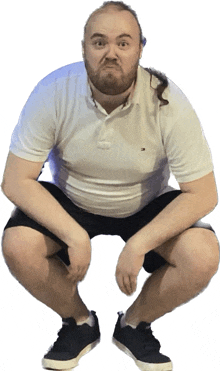 a man with a beard is squatting down wearing a white tommy hilfiger shirt