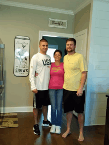 two men and a woman pose for a picture in front of a sign that says shows