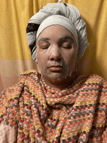 a woman with a towel wrapped around her head is wearing a face mask