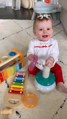 a baby girl is sitting on the floor playing with toys