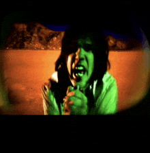 a man in a green shirt is singing into a microphone in front of a desert landscape