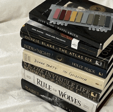 a stack of books including the atlas six and the rule of wolves