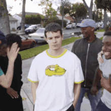 a group of people are standing on a sidewalk and one of them is wearing a shirt with a banana on it