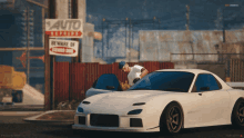 a white car is parked in front of a sign that says beware of guard dog