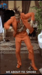 a man in an orange suit is dancing in a room with the words we about to smoke below him .