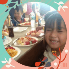 a little girl sitting at a table with plates of food and a bottle of coca cola