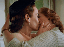 a woman in a black hat is kissing another woman in a plaid shirt