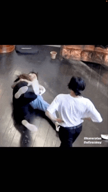 a man is kicking another man on the floor while another man looks on .