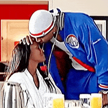 a man in a blue jacket kissing a woman on the forehead .