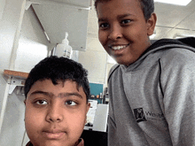 two young boys are posing for a picture and one has a sweatshirt that says wahiba primary school on it