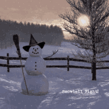 a snowman wearing a witch hat and holding a broom in a snowy field