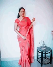 a woman in a pink saree is standing in front of a table