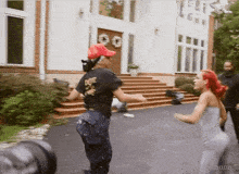 two women are dancing in front of a large white house and one of them is wearing a shirt that says do n't care