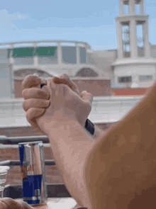 a can of red bull sits on a table next to a person holding hands