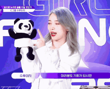 a woman holding a stuffed panda bear in front of a purple background with the letter n