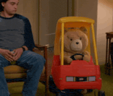 a teddy bear sitting in a little tikes car