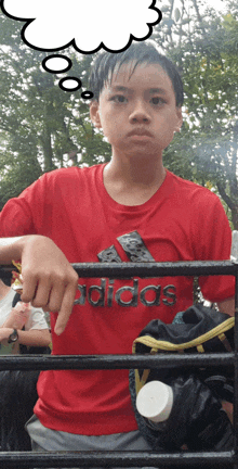 a boy wearing a red shirt that says adidas on it