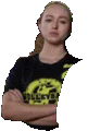 a woman is standing with her arms crossed and wearing a black t-shirt with a yellow logo on it .