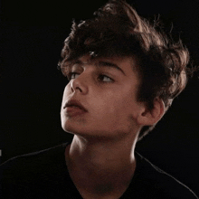 a close up of a young boy 's face with a black background