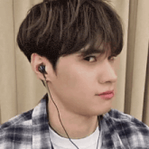 a close up of a person wearing headphones and a plaid shirt .
