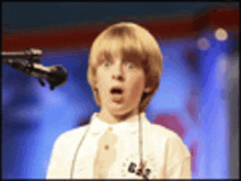 a young boy singing into a microphone with a surprised expression on his face