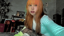 a girl with orange hair is taking a selfie in a room .