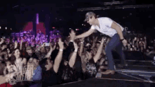 a man reaches out to shake a woman 's hand in front of a crowd at a concert sponsored by disney studios