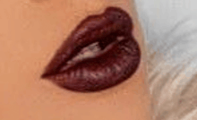 a close up of a woman 's lips with dark red lipstick on them .