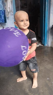 a young boy holding a purple balloon that says love