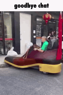 a man is sitting in a shoe shaped car on the street .