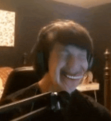 a man wearing headphones is smiling in front of a microphone in a room .