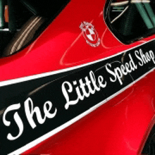 a red car with a black and white stripe that reads the little speed shop