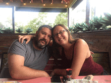 a man and a woman sit at a table with a bottle of tabasco on it