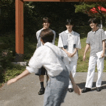 a group of young men are standing on the side of a road and one of them is jumping in the air