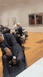 a man in a suit sleeping in a wheelchair in a museum
