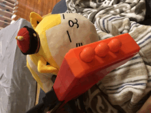 a stuffed animal laying on a bed with a clock on it that says 1:03