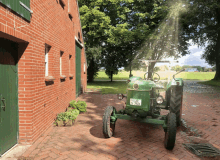 a green tractor is parked in front of a brick building and has a license plate that says tz 973