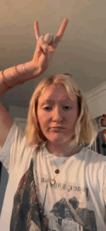 a woman wearing a t-shirt that says jack daniels makes a horn sign