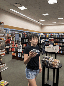 a girl in a black shirt that says ' eastern ' on it stands in a book store