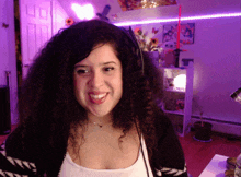 a woman wearing headphones is smiling in a room with purple lights and a sign that says " i love you "