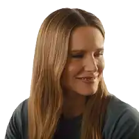 a woman with long brown hair is smiling and wearing a dark blue shirt