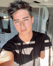 a young man with a tattoo on his arm taking a selfie