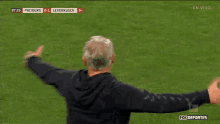 a man stands on a soccer field with his arms outstretched in front of a scoreboard that says freiburg 0-1 leverkusen