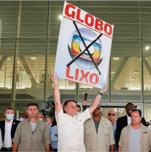 a man holds up a sign that says " globo lixo "