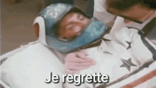 a person wearing a helmet is laying on a bed with the words `` je regrette '' written above them .