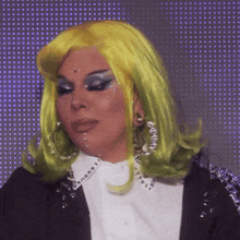 a woman wearing a yellow wig and a white shirt is making a face